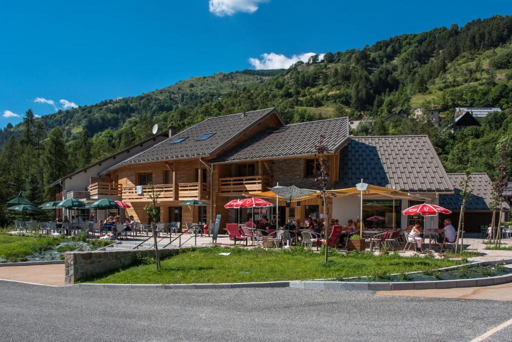 un bâtiment en rondins avec des tables et des chaises devant lui dans l'établissement Auberge de la Gravière, à Orcières