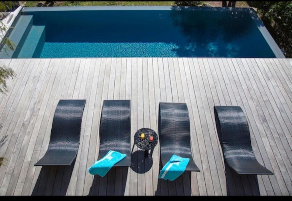 - une vue sur la piscine avec une table et des chaises dans l'établissement Villa Standing Palombaggia 10 personnes vue mer, piscine, à Porto-Vecchio
