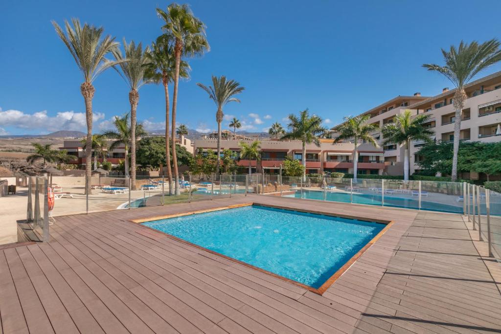 a swimming pool with palm trees and a building at Paradise Beach Bay in Adeje