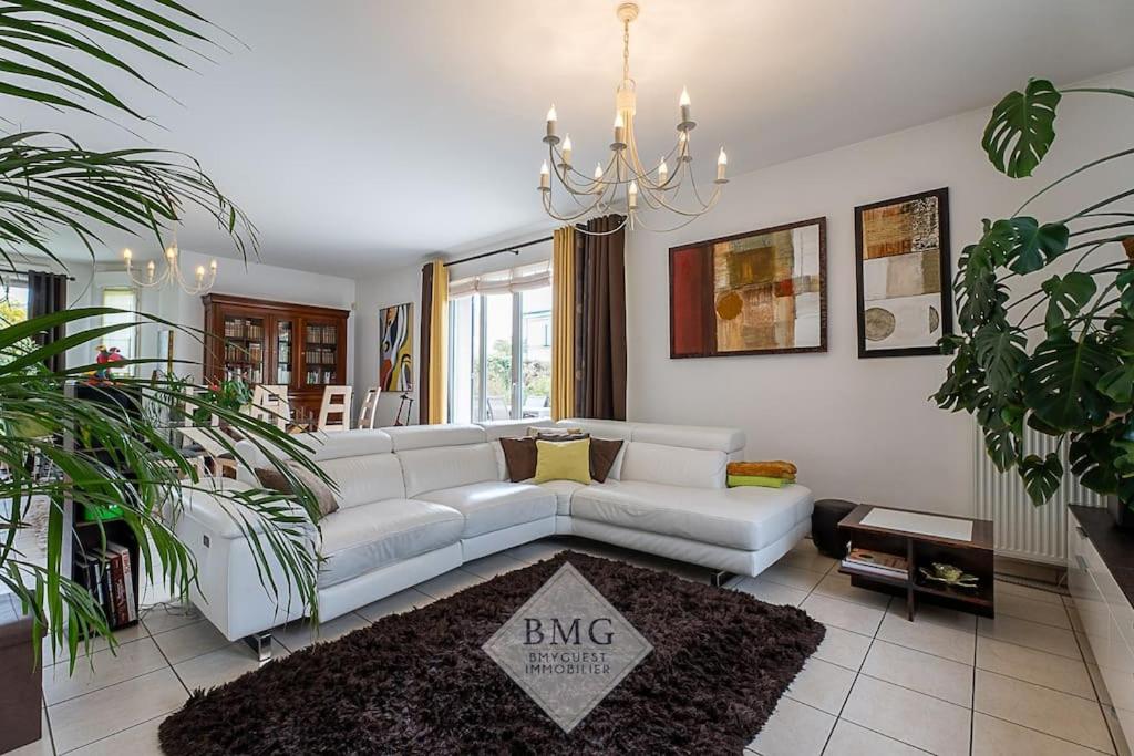 sala de estar con sofá blanco y lámpara de araña en Villa Debussy Disneyland, en Bussy-Saint-Georges