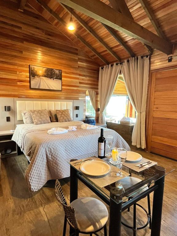 a bedroom with a bed and a table with two chairs at Cabana Alpen Ville Rural com Banheira in Bom Jardim da Serra