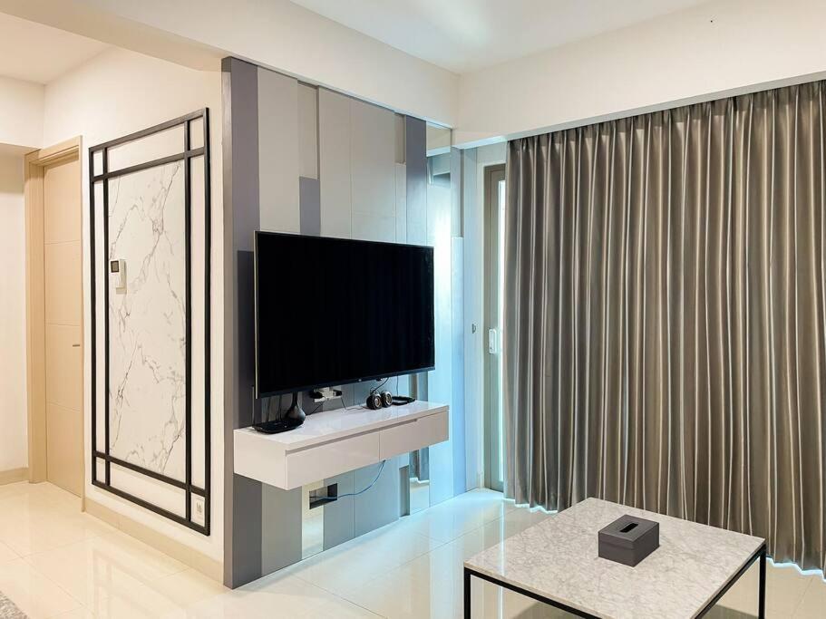 a living room with a flat screen tv and a table at The Jeewel of La Casa IV in Surabaya