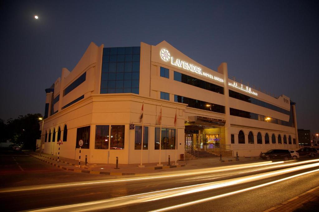 ein Gebäude an einer Stadtstraße in der Nacht mit Lichtern in der Unterkunft Lavender Hotel Sharjah in Schardscha