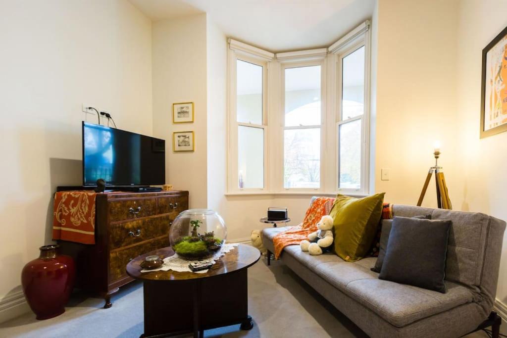 a living room with a couch and a tv at Stunning One Bedroom Apartment in Fitzroy in Melbourne