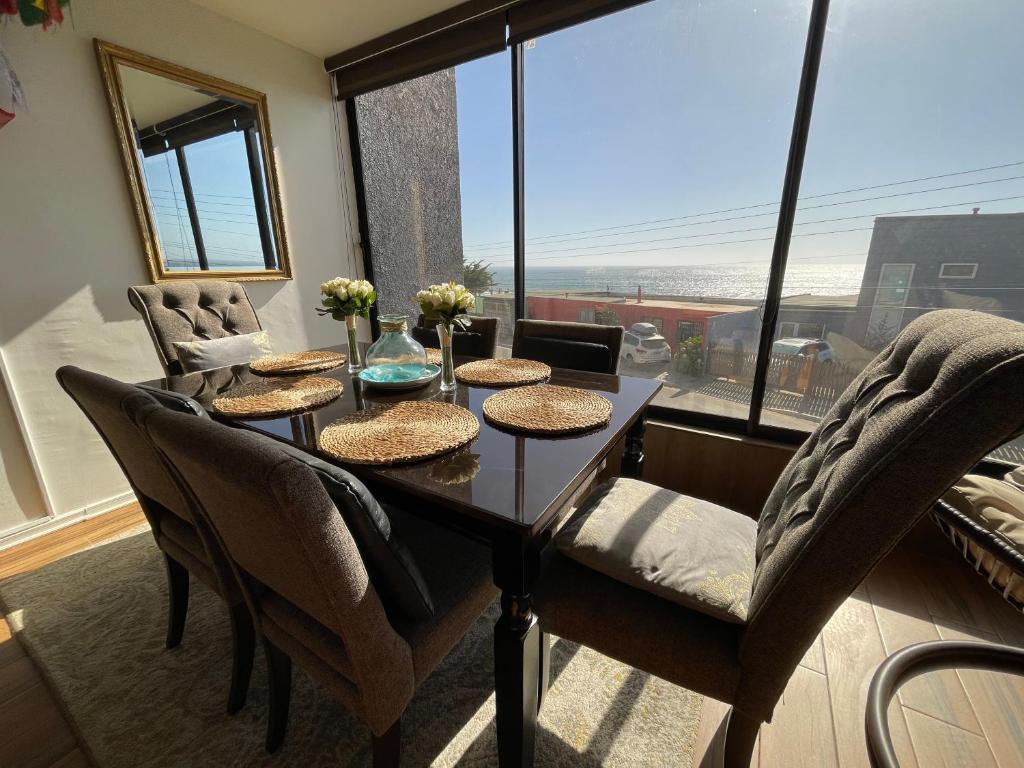 a dining room with a table and chairs and a large window at Departamento con Vista al Mar en Pichilemu in Pichilemu