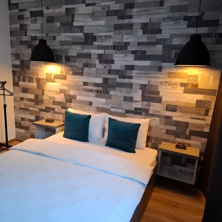 a bedroom with a bed and a brick wall at New Grey Apartament in Reghin