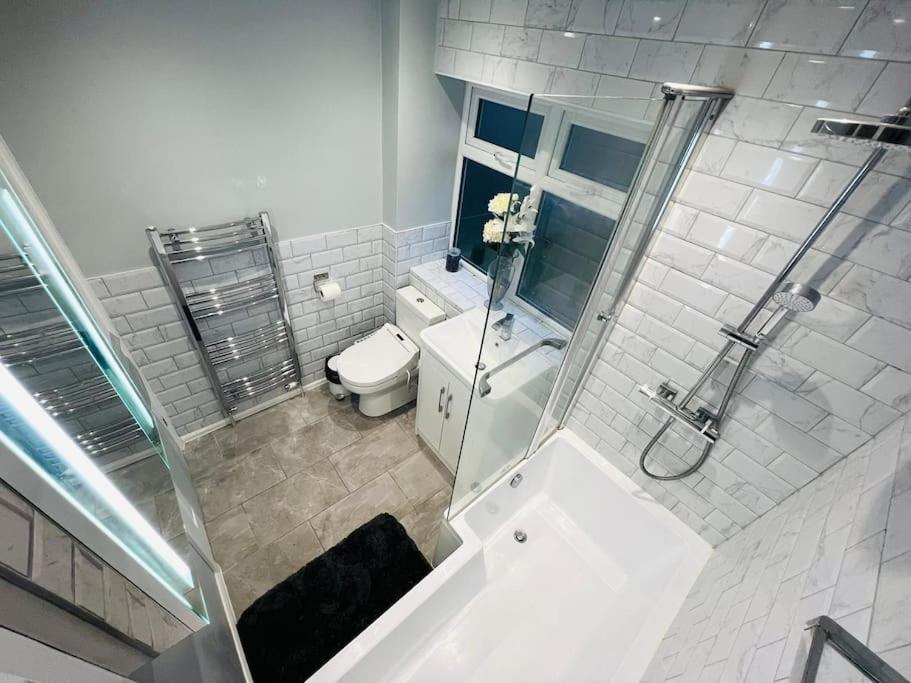 a white bathroom with a toilet and a shower at Three bedroom house in Harlow