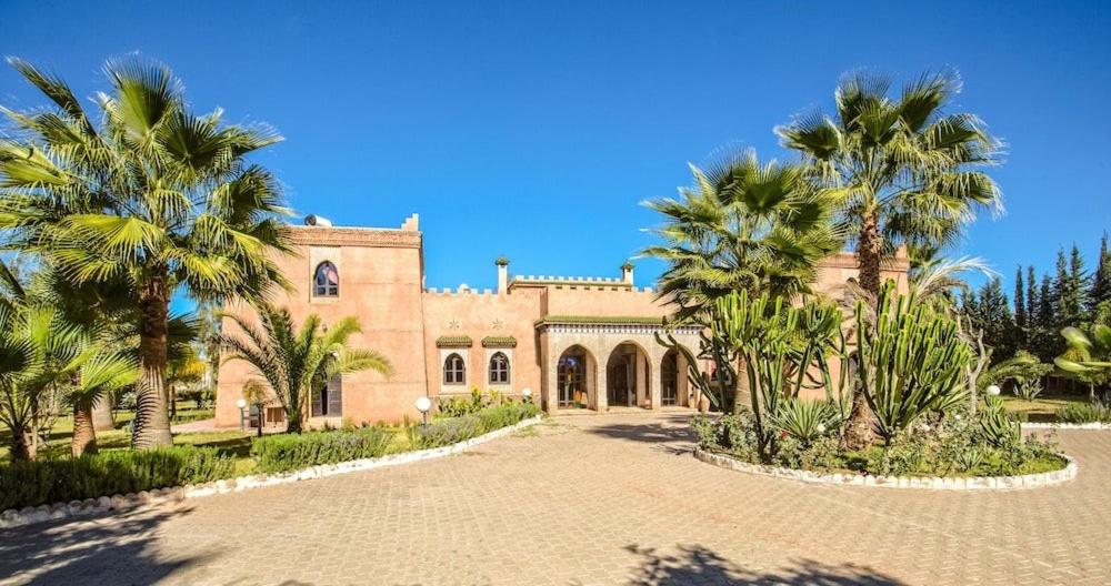 a large house with palm trees in front of it at palais ghaiat in Had Abdallah Rhiat