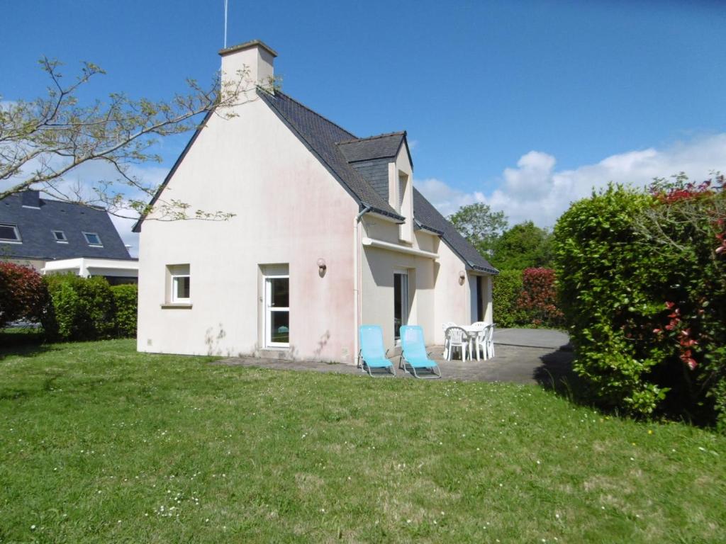 a white house with two blue chairs in the yard at Villa Anna in Sarzeau