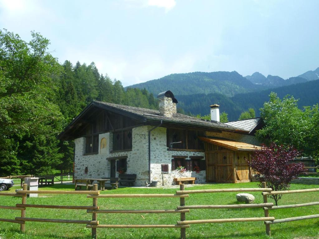 una pequeña casa en un campo con una valla en Baita Tomaselli en Pellizzano
