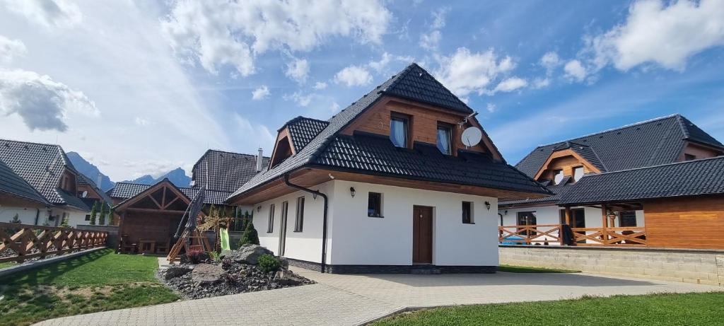 a house with a black roof and some buildings at Chata Alex in Stará Lesná