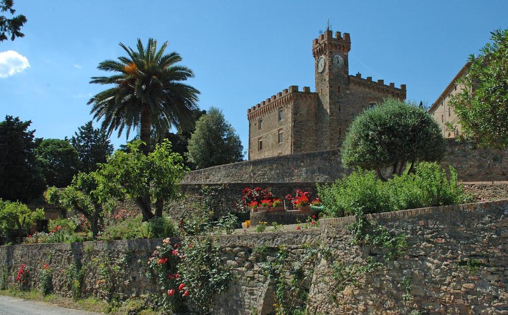 un edificio antiguo con una pared de piedra y flores en Tenuta di Casaglia, en Podere Colombaie