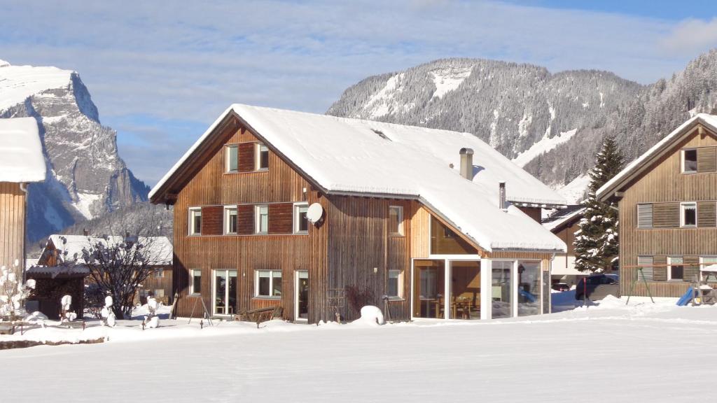 a large wooden house in the snow with mountains at Appartement Elisabeth in Schoppernau