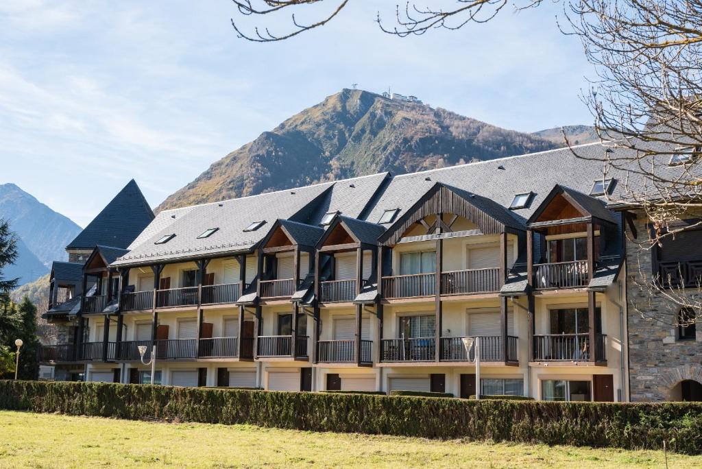 a building with a mountain in the background at Le Village des Thermes in Vignec