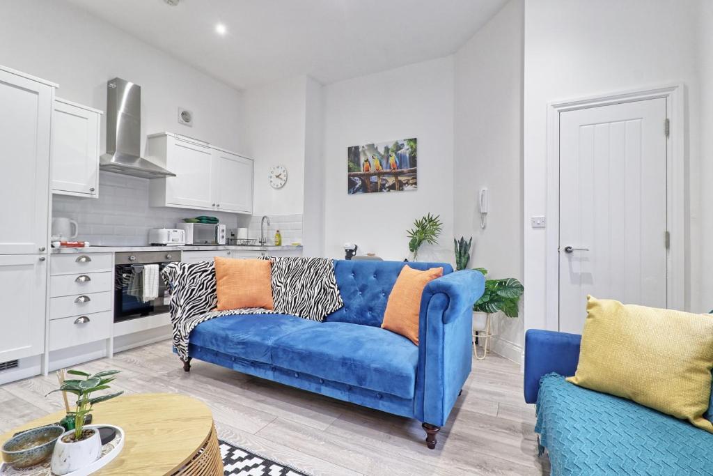 a living room with a blue couch and a kitchen at Chelmsford City Central Ground Floor Apartment Next To Town Centre in Chelmsford