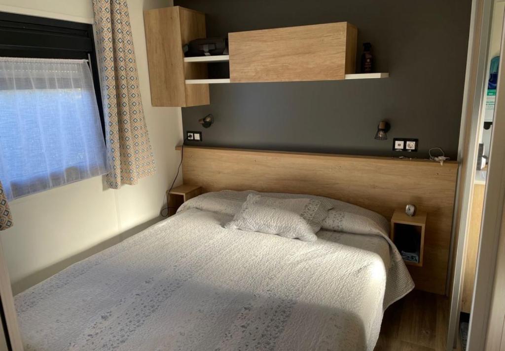 a small bedroom with a bed and a window at Location Mobilhome Bahiana 8 personnes Camping 4 étoiles La Réserve Gastes in Gastes