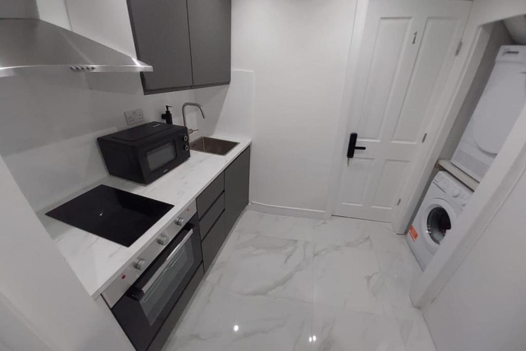 a small white kitchen with a microwave and a sink at London Euston 4 minute walk away in London