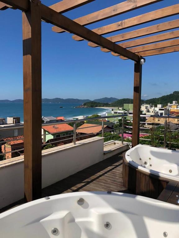 a bath tub on a balcony with a view of the ocean at Villa Maciel Bombinhas in Bombinhas