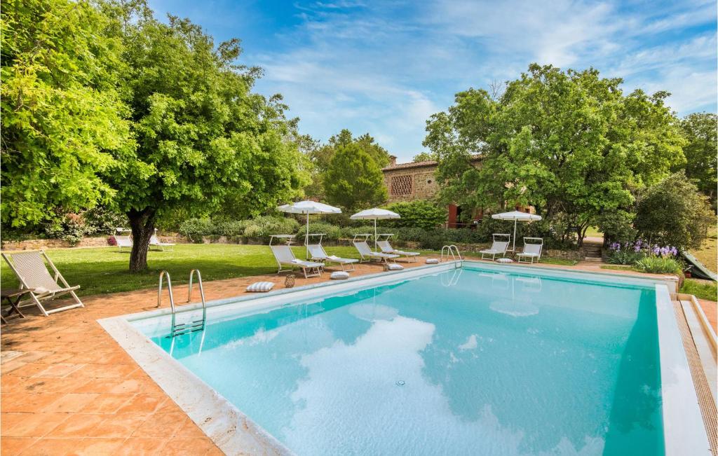 a swimming pool with chairs and umbrellas in a yard at Beautiful Home In Rapolano Terme Si in Rigomagno