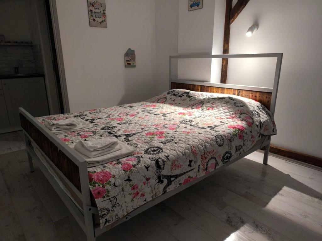 a bedroom with a bed with a floral quilt on it at Apartment By the River in Niš