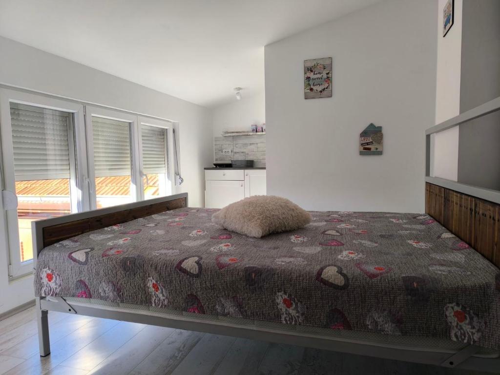 a bedroom with a bed in a room with windows at Apartment By the River in Niš