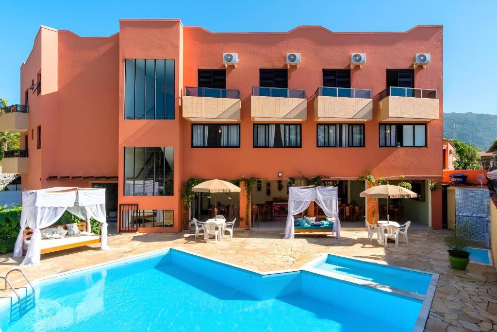 a hotel with a swimming pool in front of a building at Hotel Ponta das Toninhas in Ubatuba