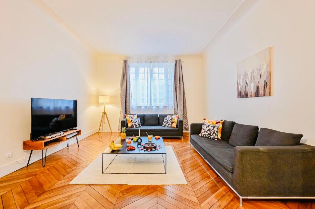 un salon avec un canapé et une télévision dans l'établissement Grand appartement Parc des princes Paris 16, à Paris
