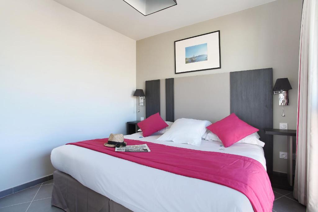 1 dormitorio con 1 cama grande con almohadas rosas y blancas en Odalys City Marseille Prado Castellane, en Marsella