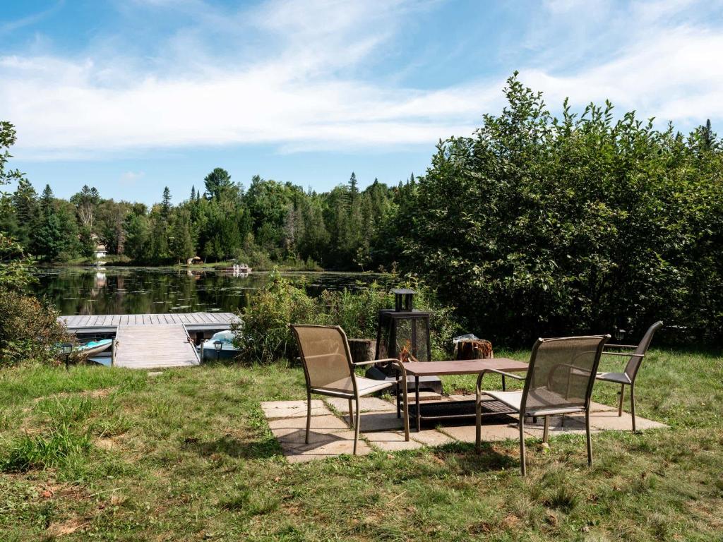 a table and chairs sitting on a patio near a lake at Le Lac Apaisant - Rustic Haven by the Water in Saint-Calixte