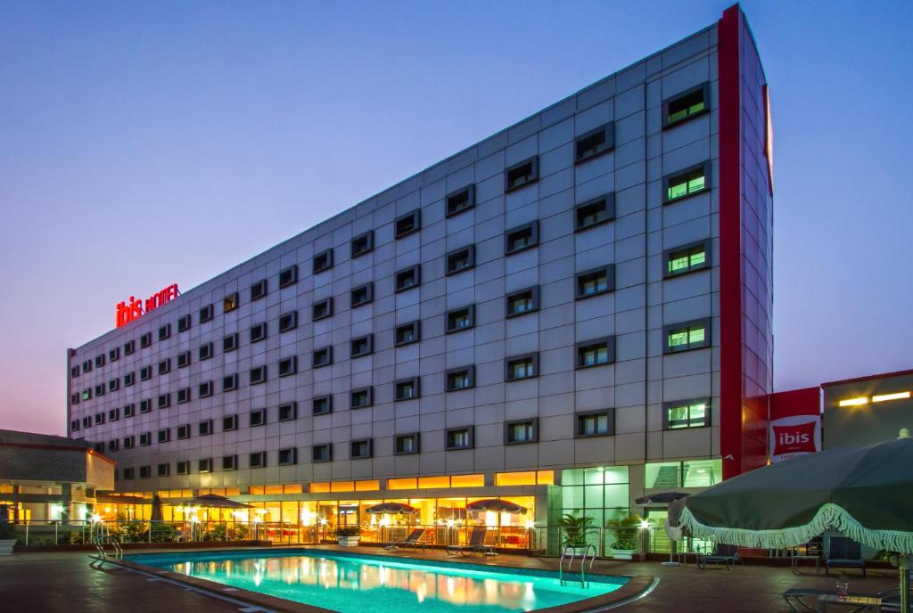 een hotel met een zwembad voor een gebouw bij Ibis Lagos Ikeja in Ikeja