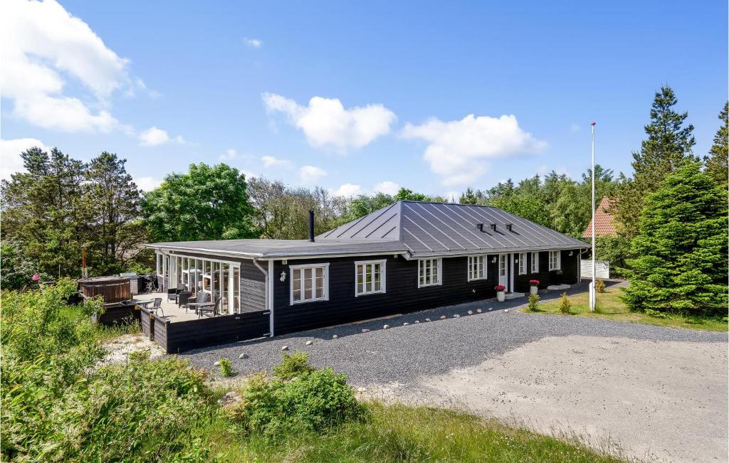 una casa con techo negro en una entrada de grava en Eight-Bedroom Holiday Home In Norre Nebel, en Nørre Nebel