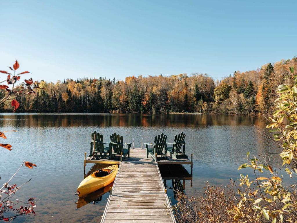 a dock with chairs and a boat on a lake at Le Plein Sud - Your ideal getaway by Lake Lise in Chertsey