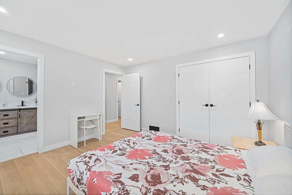 a white bedroom with a bed with a floral bedspread at Flora's House in Calgary