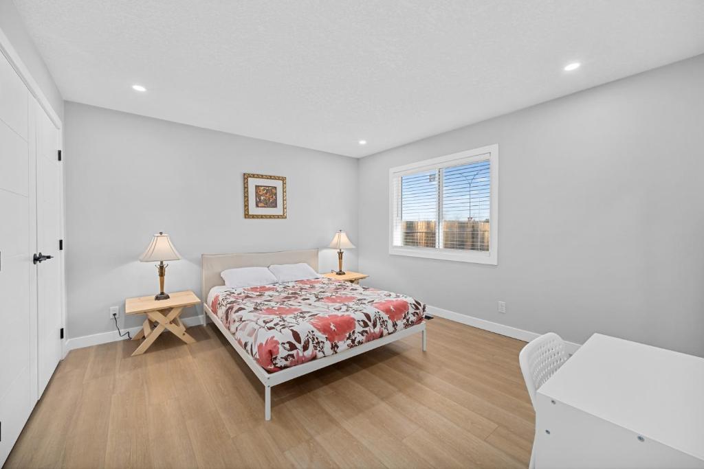 a white bedroom with a bed and a window at Flora's House in Calgary