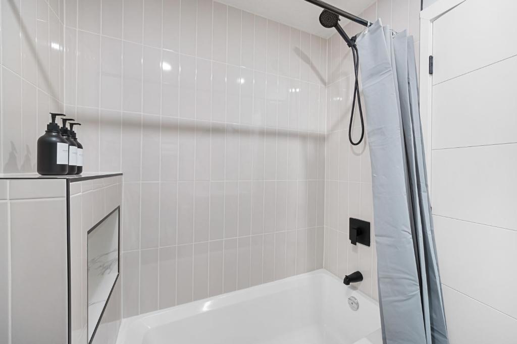 a white bathroom with a shower and a sink at Flora's House in Calgary