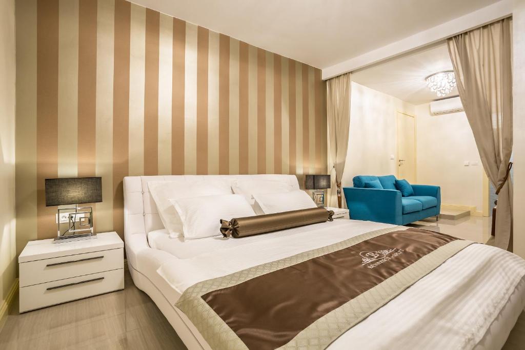 a bedroom with a large bed and a blue chair at Guest House Benedict in Split