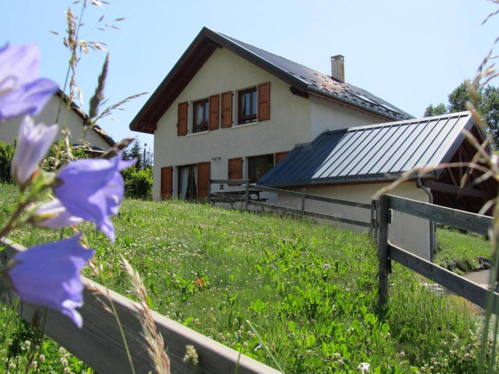 une maison avec des fleurs violettes devant une clôture dans l'établissement Gîte Du Col Vert, à Villard-de-Lans
