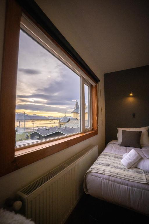 a bedroom with a window with a view of a beach at Pristine Patagonia Hotel in Puerto Natales