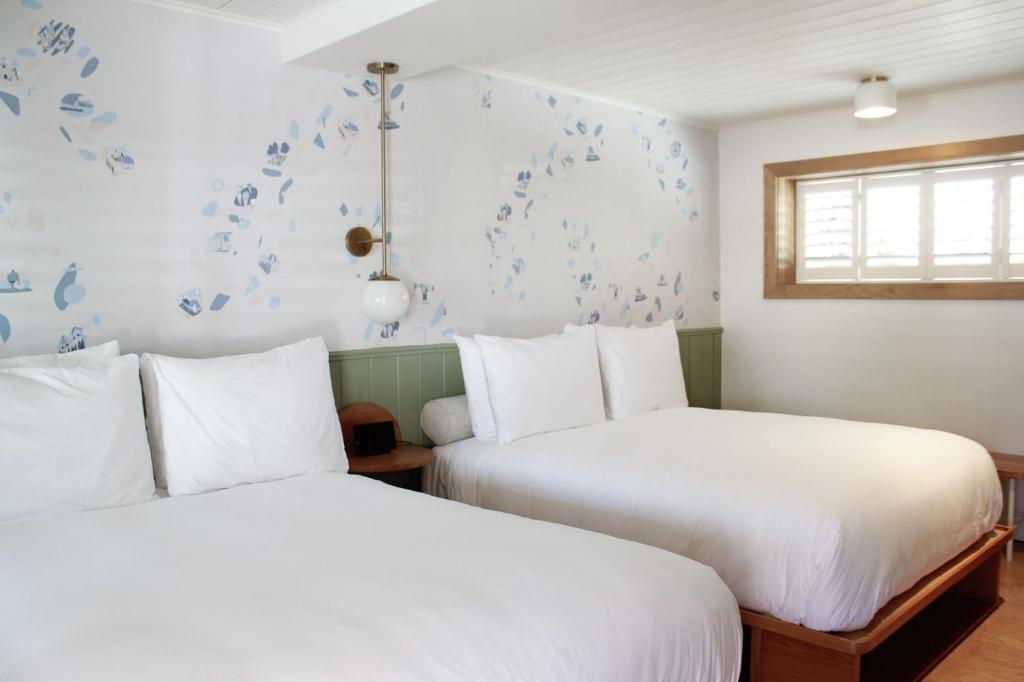 two beds in a room with blue butterflies on the wall at The Beach Motel in Southampton