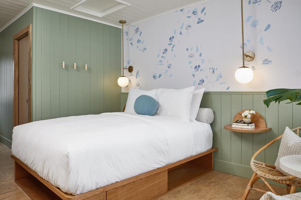 a bedroom with a bed with white sheets and blue wallpaper at The Beach Motel in Southampton