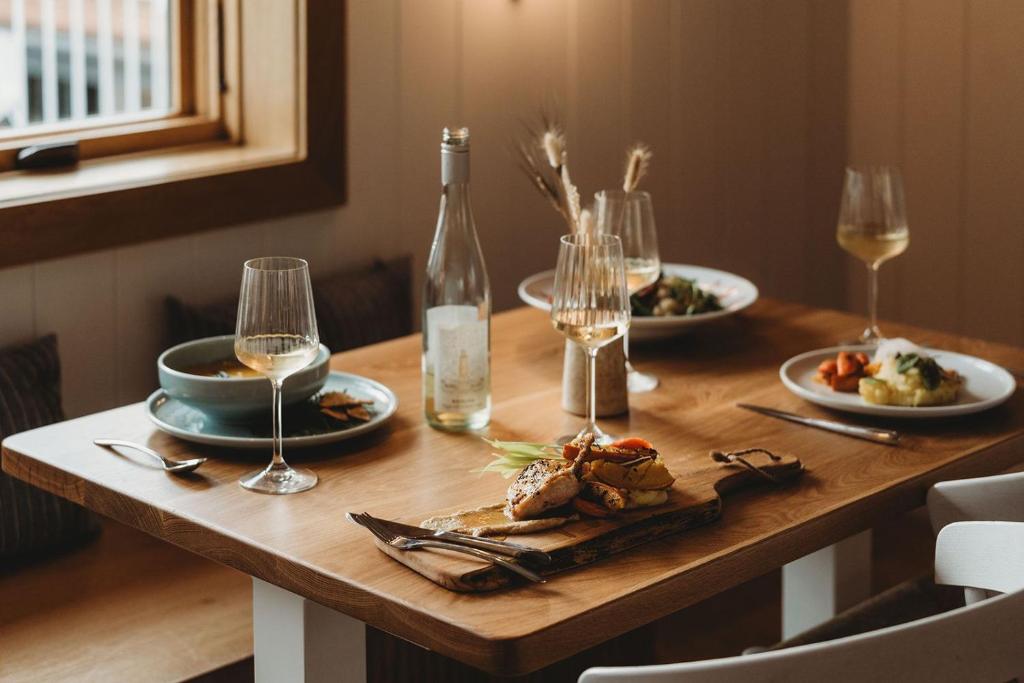 a wooden table with plates of food and wine glasses at The Beach Motel in Southampton