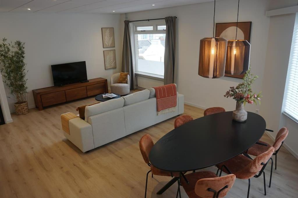 a living room with a table and a couch at Zen Beach Apartment in Noordwijk aan Zee