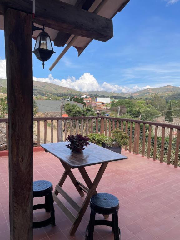 a table and two stools on a balcony with a view at Casa Agua Dulce in Samaipata