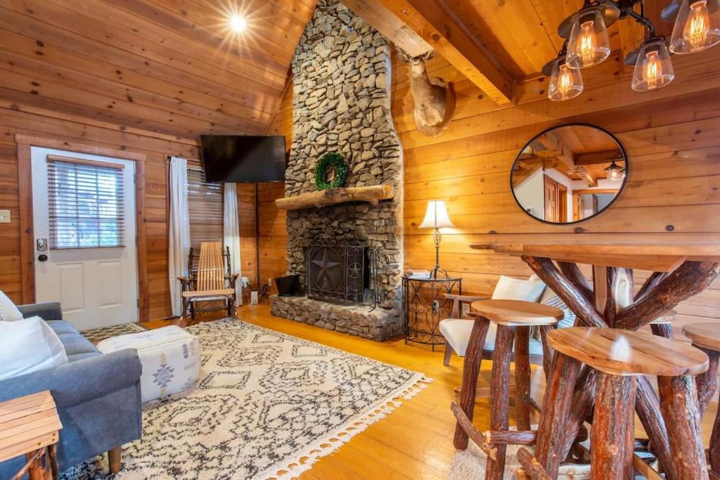 a living room with a stone fireplace in a log cabin at Cozy Cabin Smoky Mountains - Hot tub, pool, & golf in Townsend