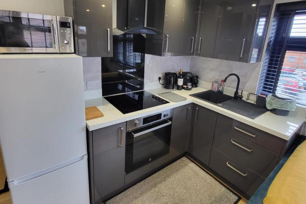a kitchen with black cabinets and a white refrigerator at Town Centre Modern 1 Bed self-contained Apartment in Newbury