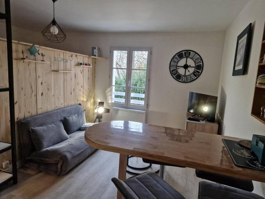 - un salon avec une table et une horloge murale dans l'établissement Appartement studio Pompon, Wifi, 2 couchages, charme, centre historique, à La Rochelle