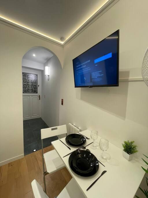 un salon avec une table et une télévision au mur dans l'établissement Cosy Appart Paris 8e champs elysees Miromesnil, à Paris