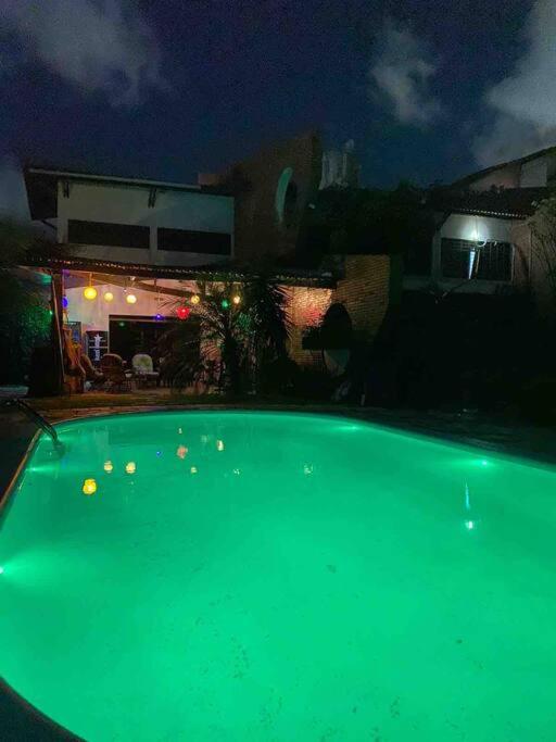 a green swimming pool in a yard at night at mansão com churrasqueira sinuca piscina aquecida in Natal