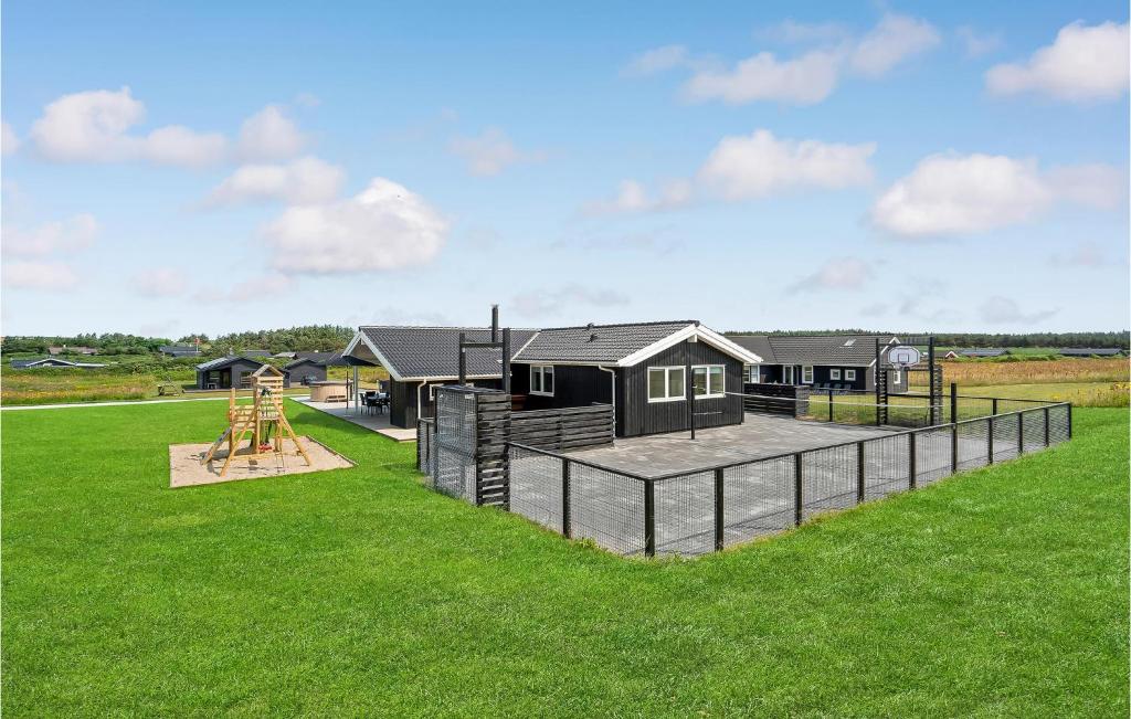 a house with a playground in a grass field at Lovely Home In Løkken With Sauna in Løkken