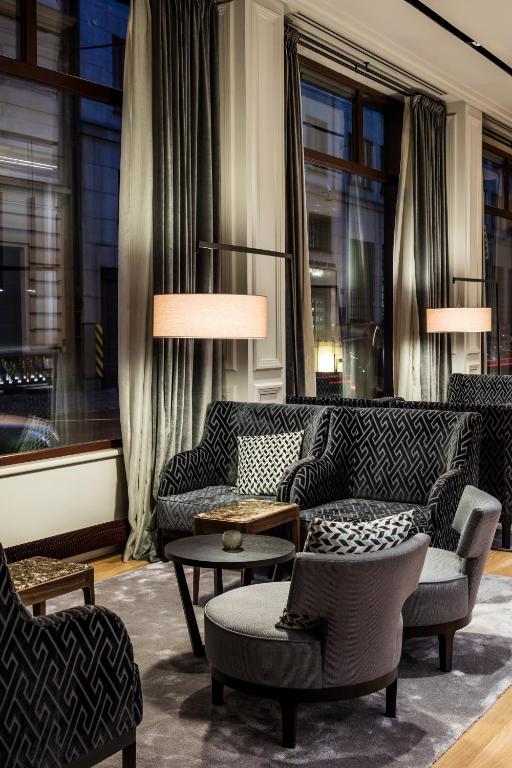 a living room with couches and tables and windows at BoHo Prague Hotel - Small Luxury Hotels in Prague